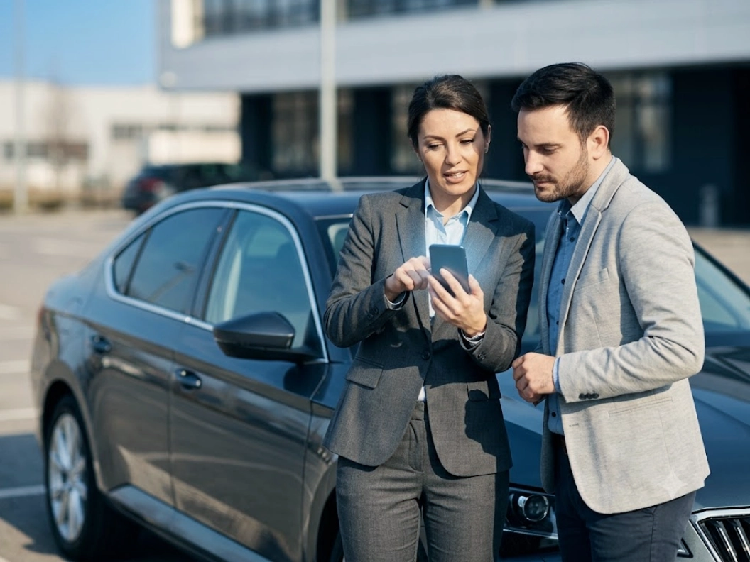 Zwei Berufstätige prüfen ihr Fahrtenbuch in der autoaid App am Fahrzeug